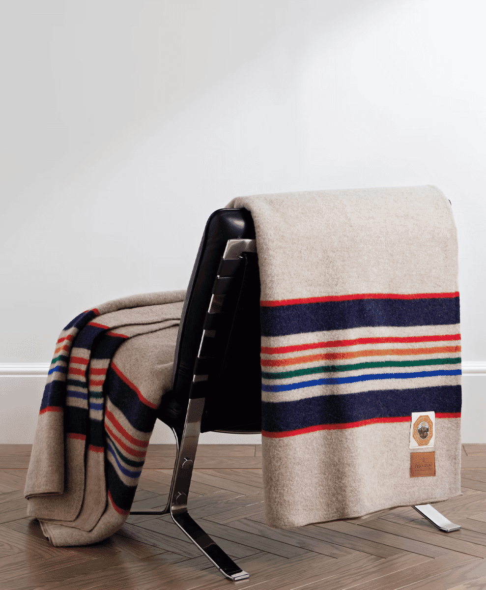 A colorful striped wool blanket draped over a black leather chair in a modern living room.