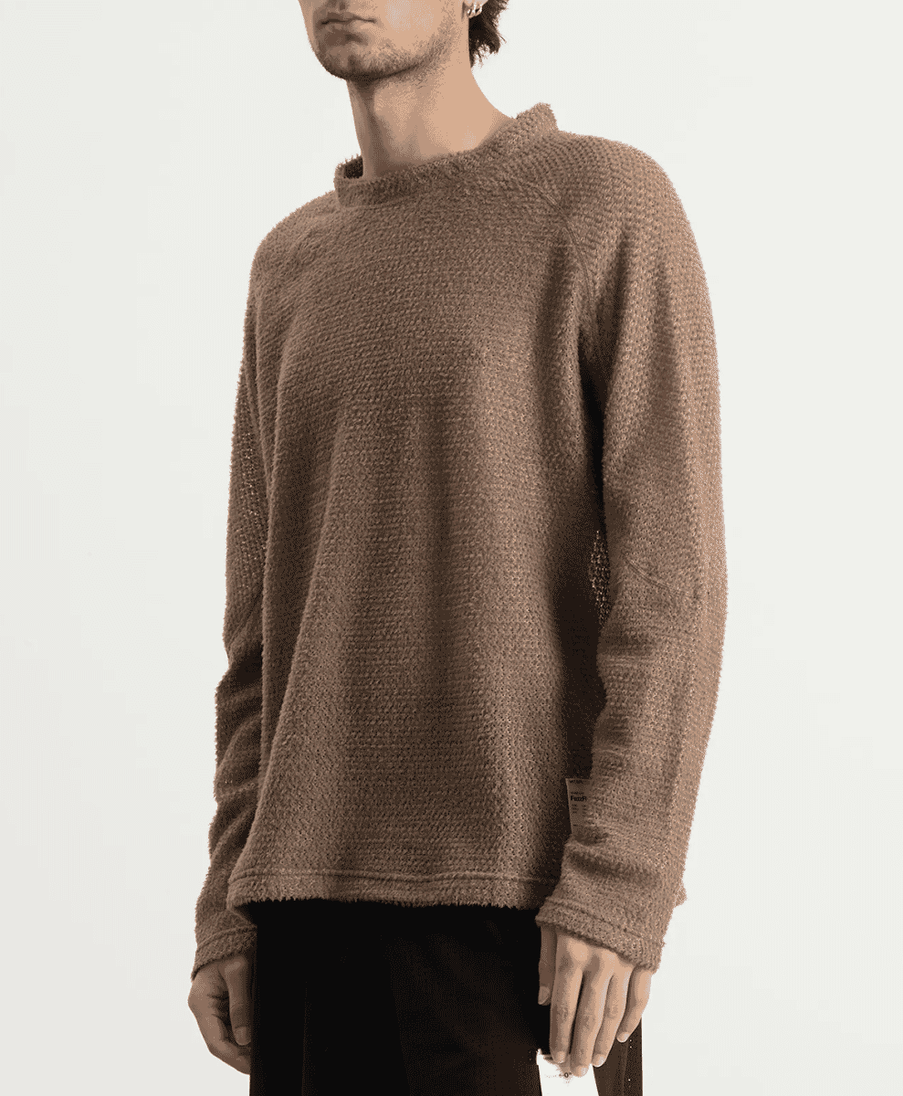 Close-up of a man wearing a textured brown knit sweater with ribbed cuffs.