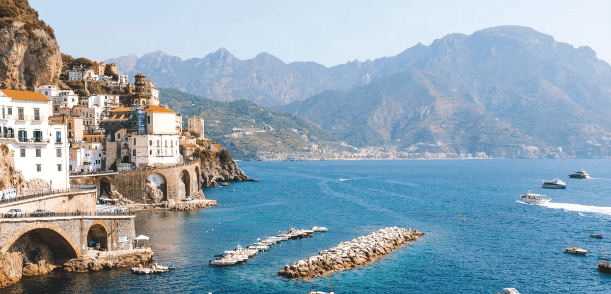Scenic coastal view of white buildings perched on cliffs overlooking turquoise Mediterranean waters.