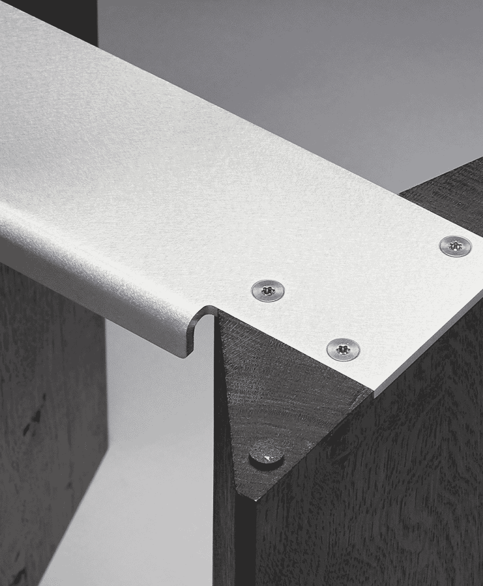Close-up of a modern metal bracket fastened with screws onto dark wood furniture.