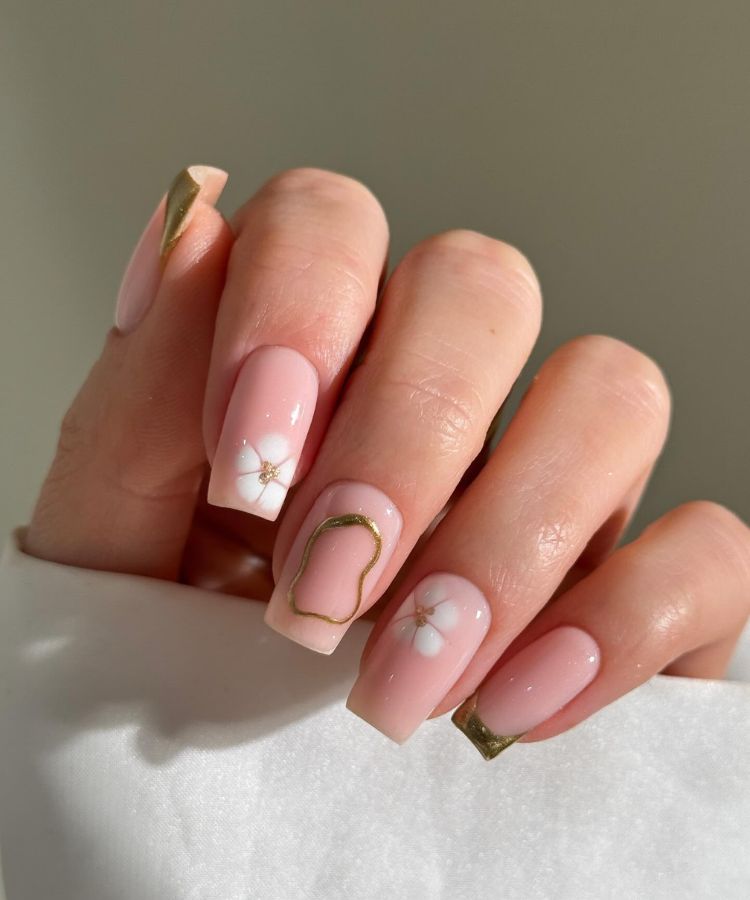 Nude nails decorated with intricate gold floral line art.