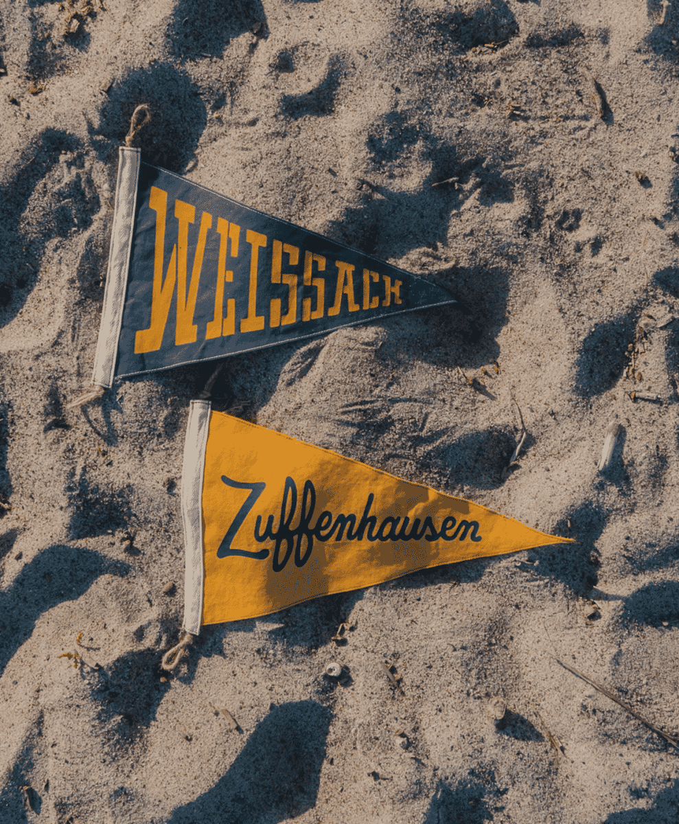 Vintage-style Weissach and Zuffenhausen pennants on the sand.