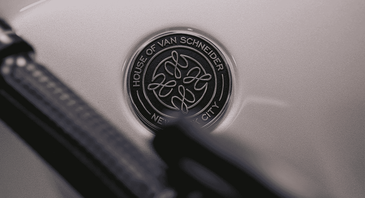 Close-up of a bronze circular emblem engraved with 'HOUSE OF VAN SCHNEIDER NEW YORK CITY'.