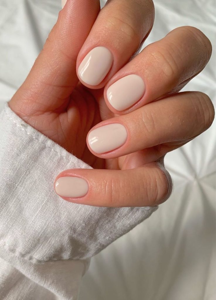 Manicure featuring a soft milky white finish on almond-shaped nails.