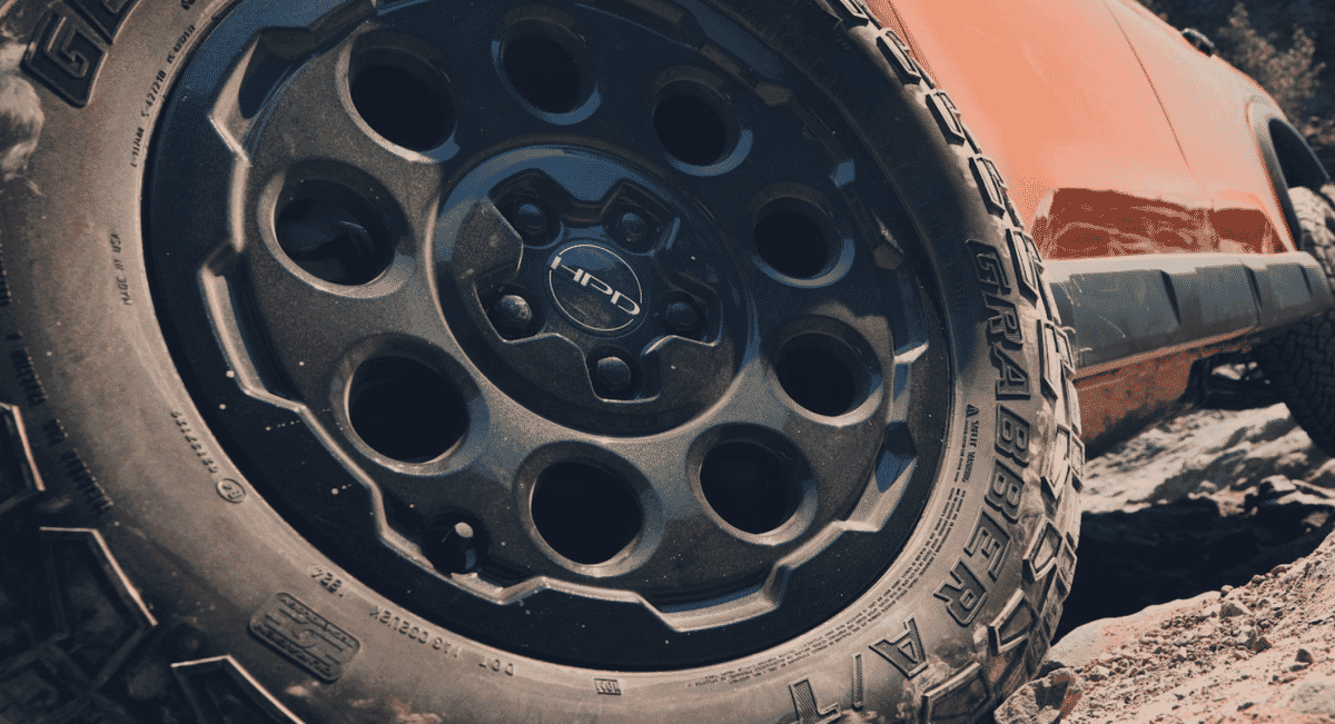 Close-up of a rugged off-road tire with 'GRABBER A/T' branding on an orange SUV.