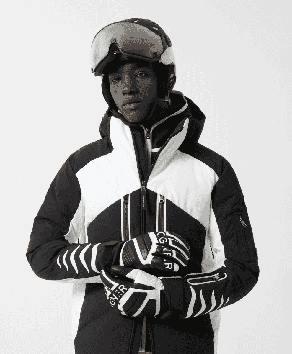 A model in a black-and-white patterned high-performance ski jacket and helmet.