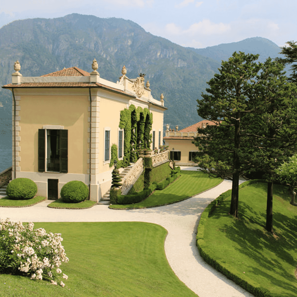 Classical Italian villa architecture surrounded by manicured gardens with a mountain backdrop.