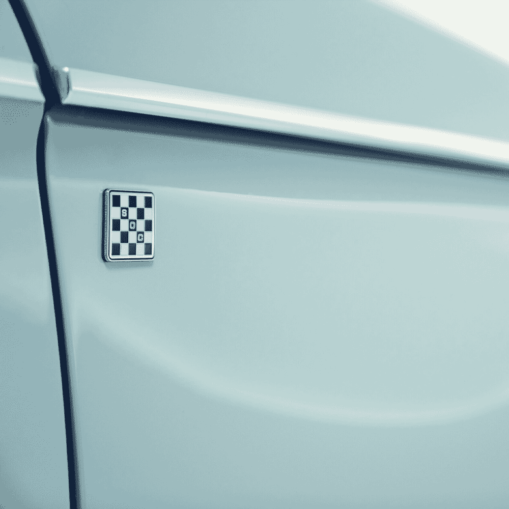 Detail shot of a checkered SDC logo on the side of a light blue car door.