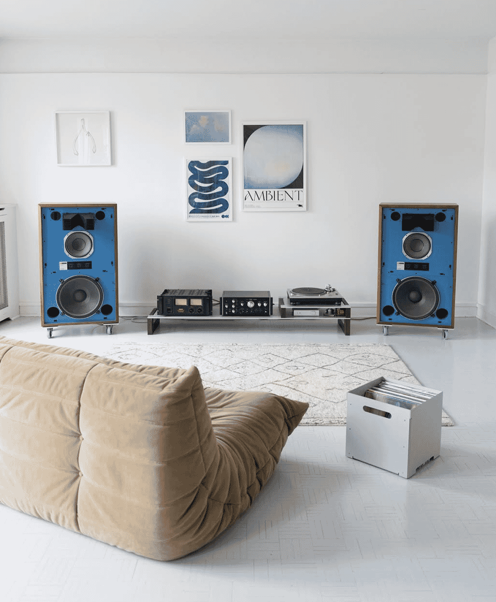 Minimalist living room with a beige tufted sofa and vintage blue speakers on a low shelf.