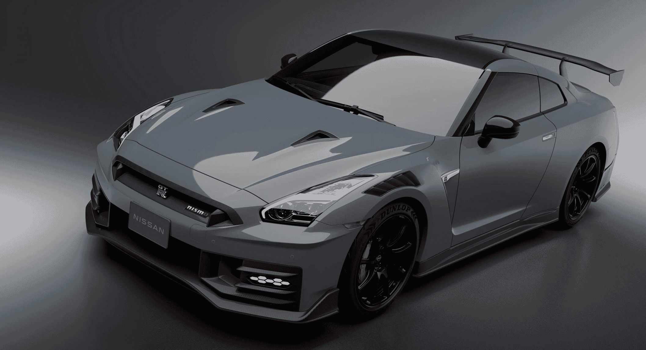 Studio shot of a gray Nissan GT-R NISMO with dramatic lighting focusing on its carbon fiber aerodynamic features.