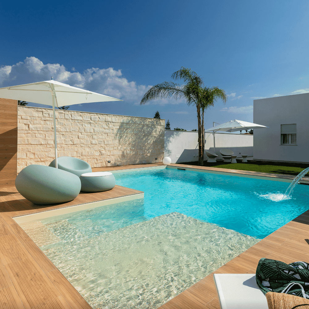 A sunlit poolside scene with modern lounge furniture and a palm tree, focusing on luxury leisure design.