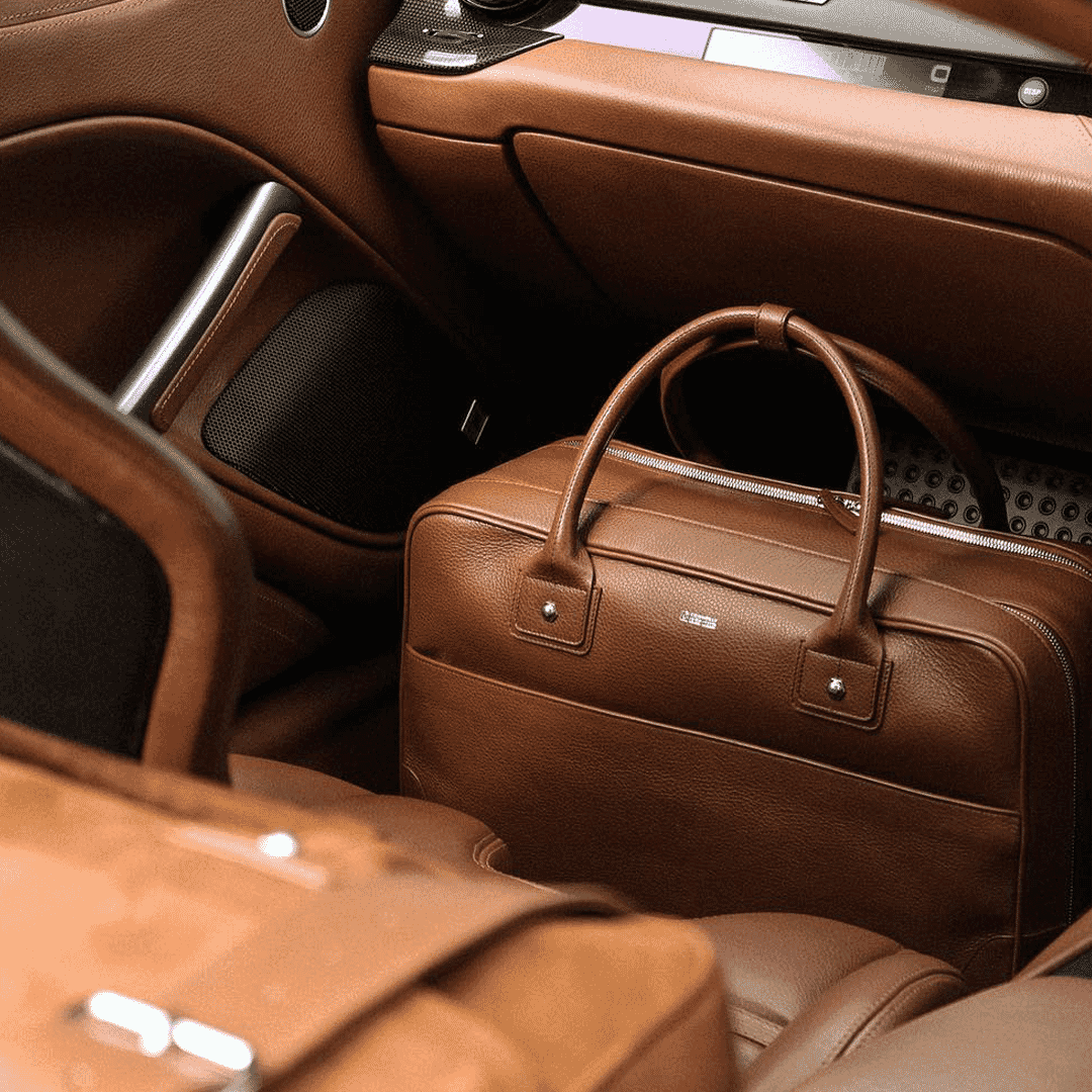 Brown leather briefcase resting on tan leather seats inside a luxury car interior.