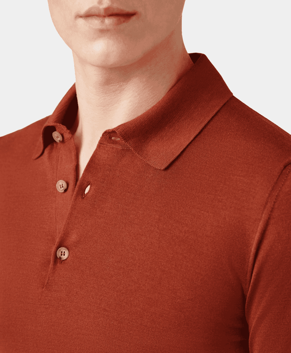 Close-up of a man wearing a terracotta-colored knitted polo with wooden buttons.