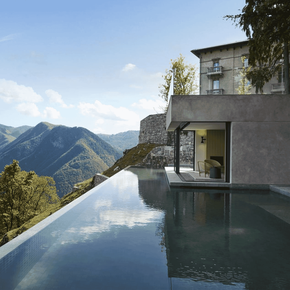 A modern stone villa with an infinity pool overlooking lush green mountain ranges.
