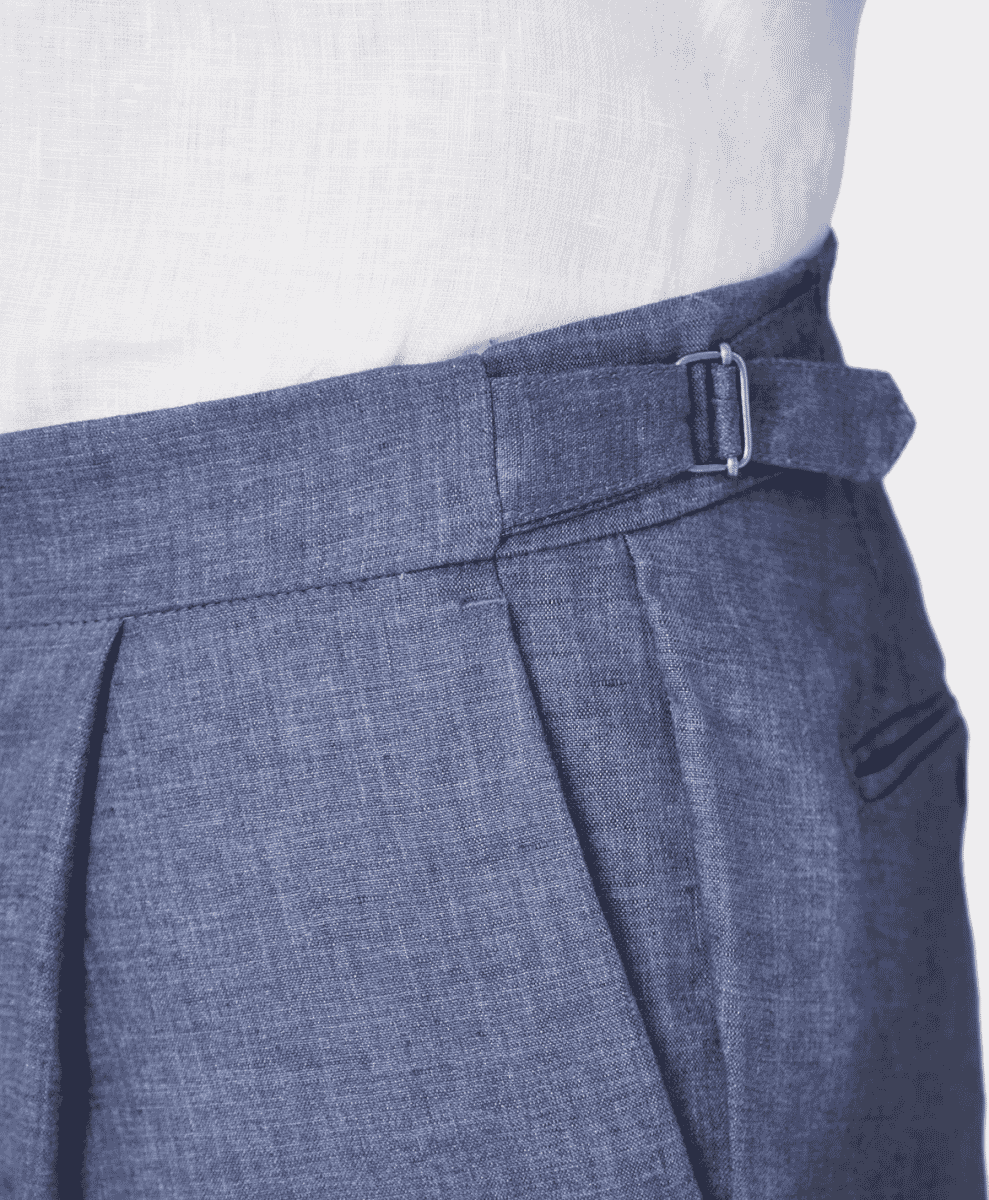 Close-up of dark gray pleated trousers with a refined belt buckle and textured white shirt.