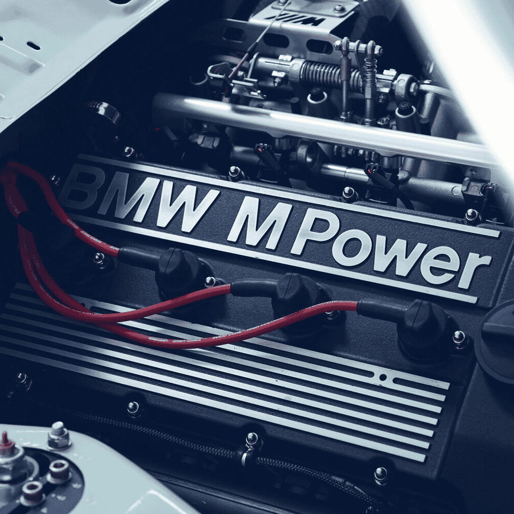 Close-up of a BMW M Power engine with red spark plug wires and metallic finishes.