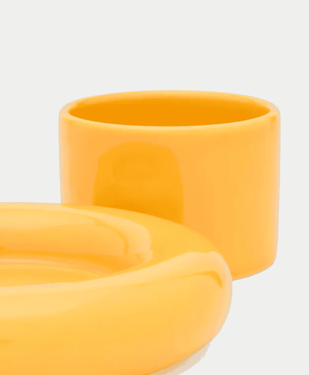Two glossy mustard-yellow ceramic containers against a white background.