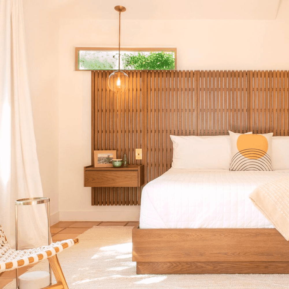 Modern minimalist bedroom featuring a wooden slatted headboard and warm natural lighting.