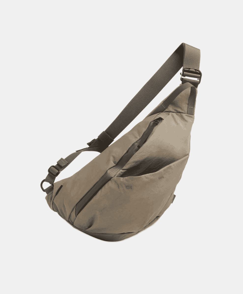 A beige tactical-style sling bag with multiple compartments and adjustable straps.