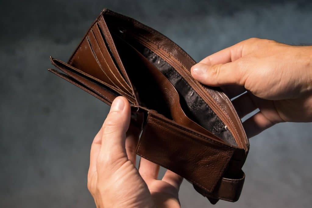 Close-up of a person's hands holding an open brown leather wallet to reveal its internal pockets.