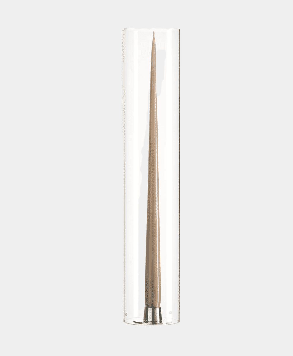 A tall beige taper candle inside a transparent glass holder with a metallic base.