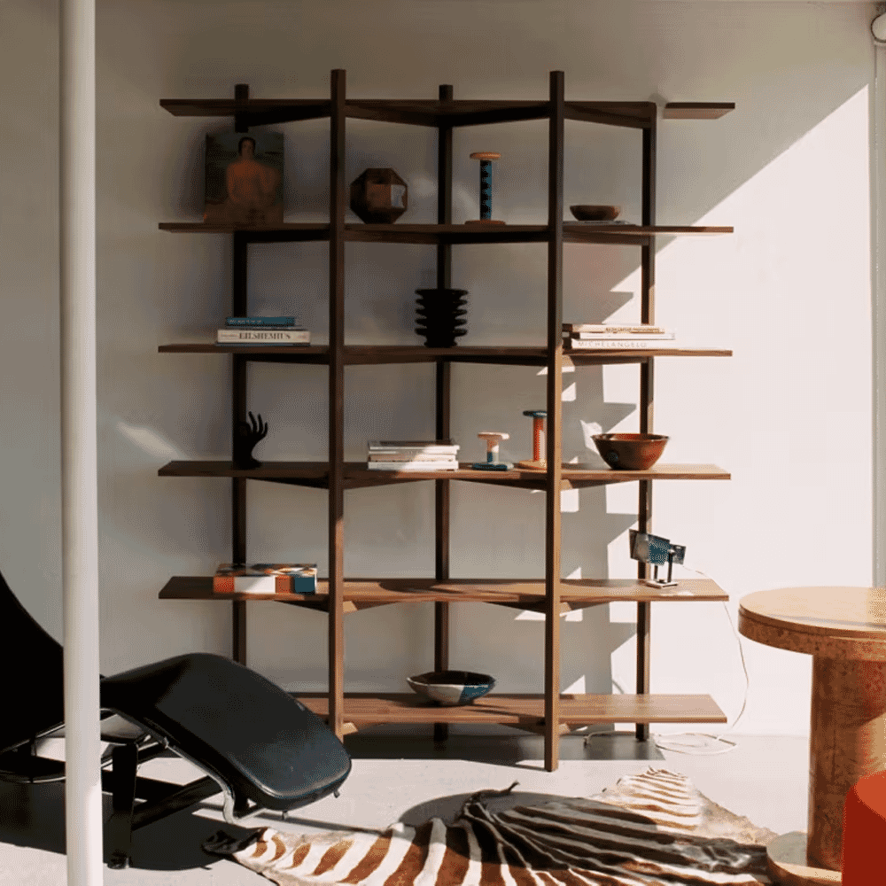 Modern wooden bookshelf with decorative objects and a lounge chair on a zebra-print rug.
