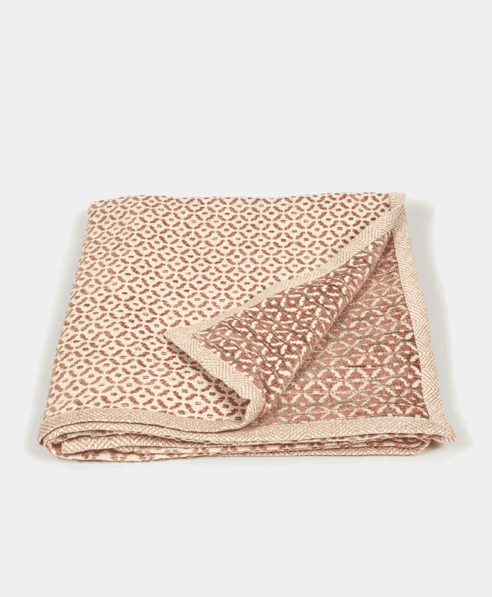 Folded geometric throw blanket in terracotta and beige tones.