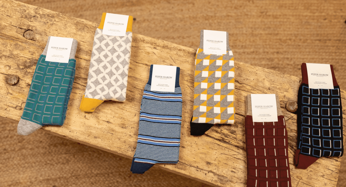 Six pairs of geometric patterned socks displayed on a rustic wooden plank.