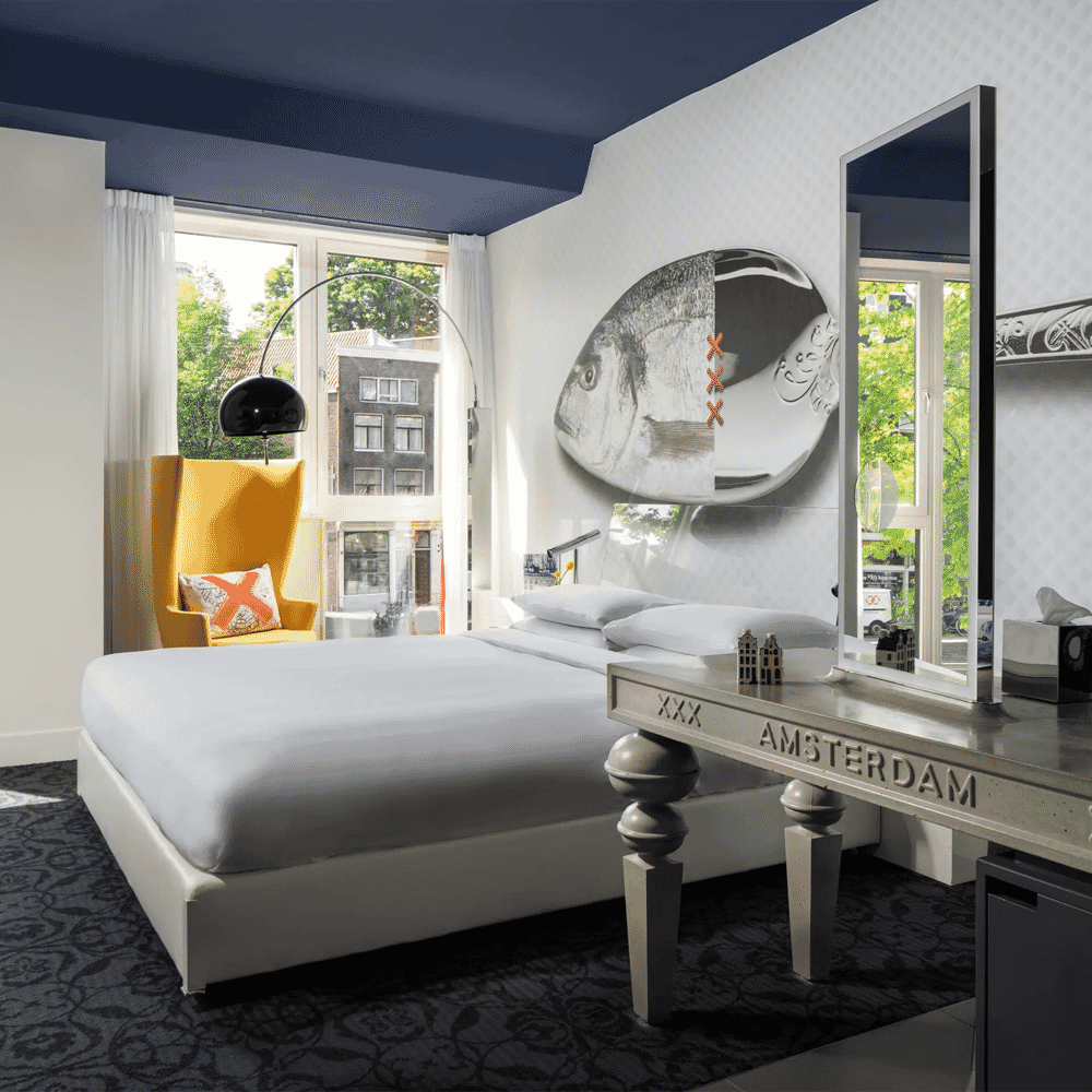 Modern hotel room with Amsterdam-themed decor and large windows.