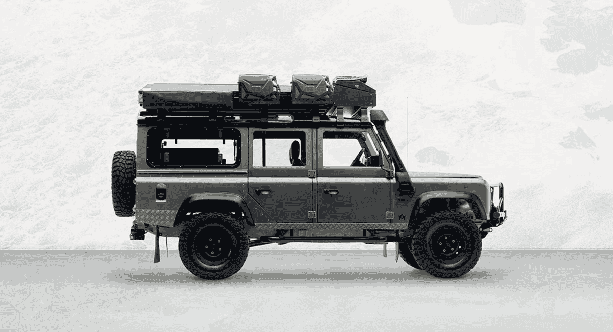 Full body studio shot of a dark gray Land Rover Defender equipped with all adventure gear.