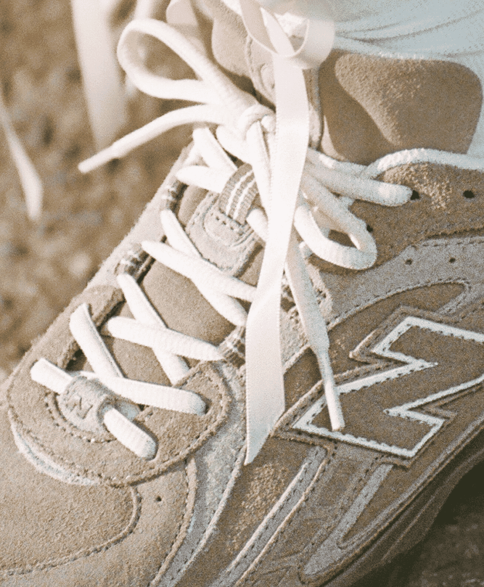Close-up of the beige suede texture and iconic 'N' logo on a New Balance sneaker.