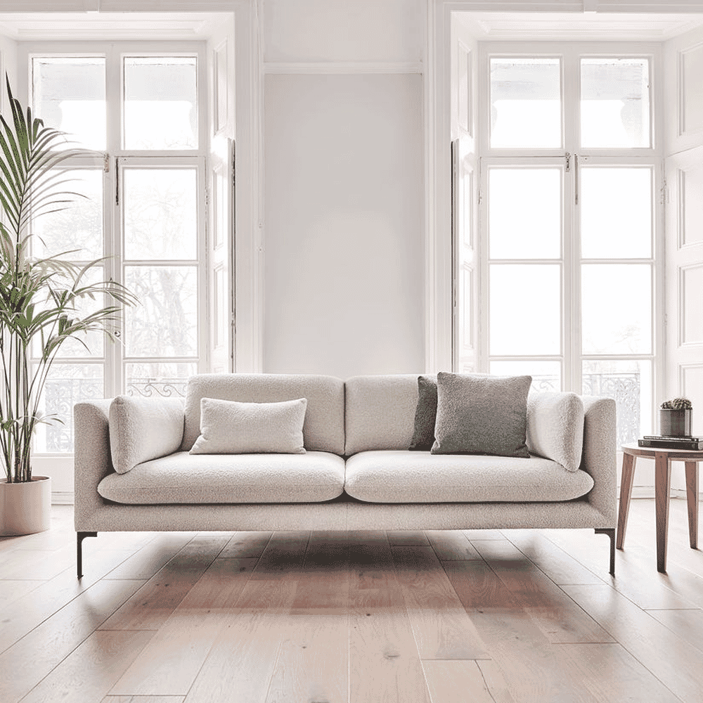 Close-up of a light beige textured sofa with neutral pillows in a bright room.
