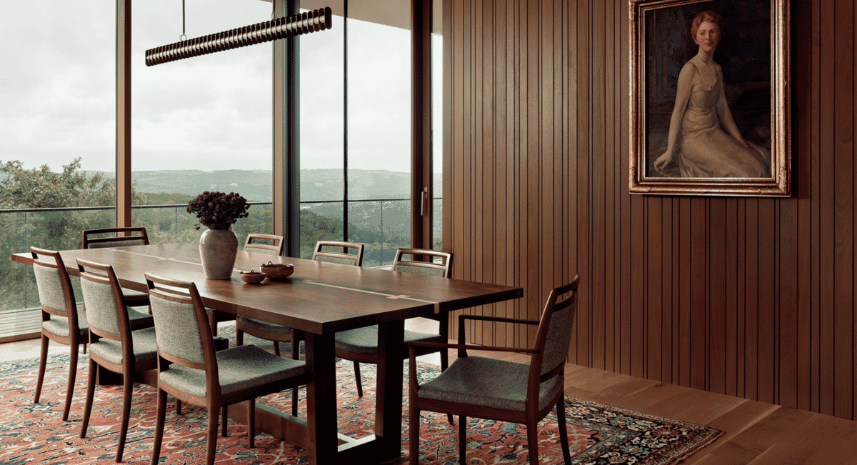 Dining room with a vintage portrait on a wood-paneled wall overlooking hills.