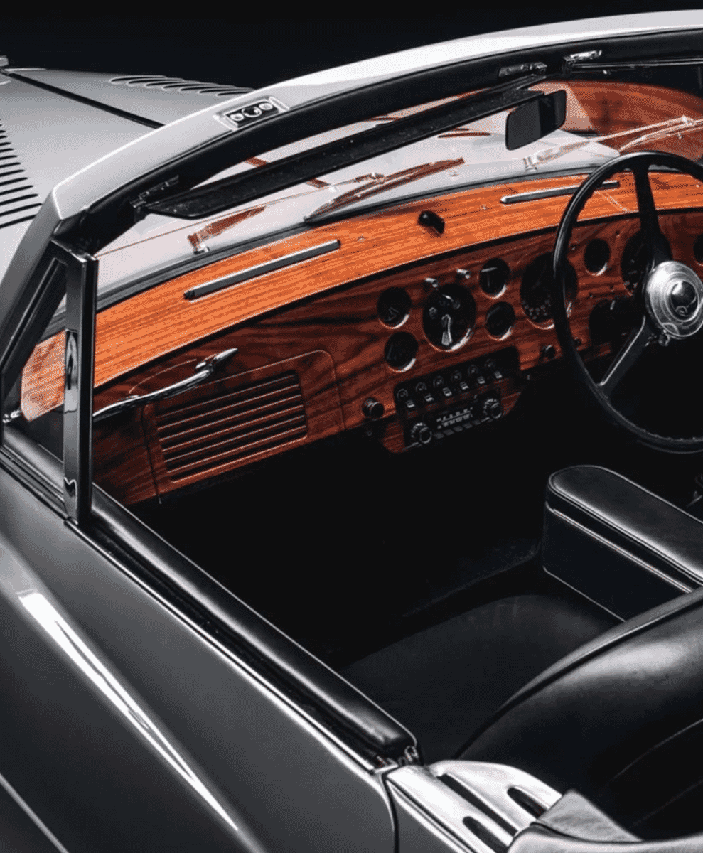 Interior of a classic 1953 Bentley featuring wood paneling and black leather seats.