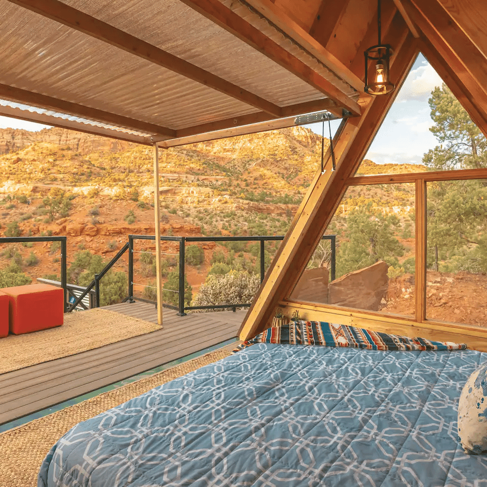 Interior of a wooden A-frame cabin featuring views of red rock desert scenery.