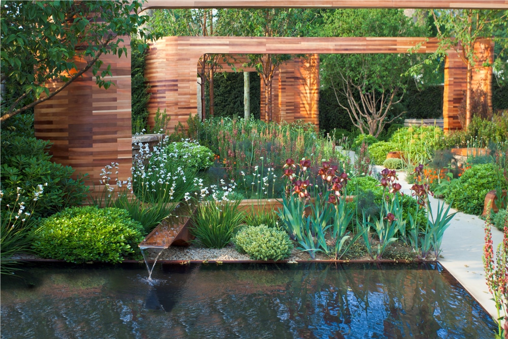 Close-up of a garden water feature with a small waterfall and reflective pool surrounded by contemporary landscaping.