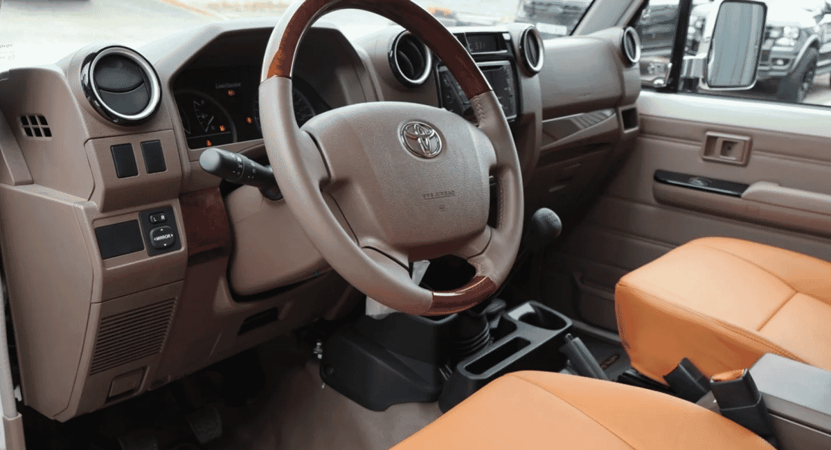 Interior view of the Toyota Land Cruiser featuring tan leather seats and a wood-trimmed steering wheel.