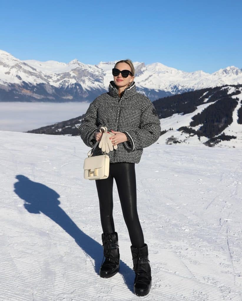 Woman wearing a black-and-white houndstooth puffer jacket and leather leggings.