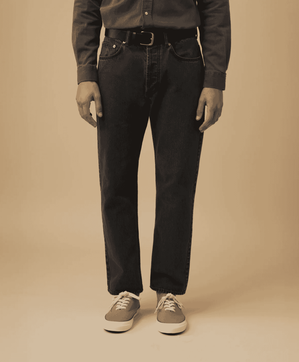 Man modeling dark-wash straight-leg selvedge denim jeans in a studio setting.