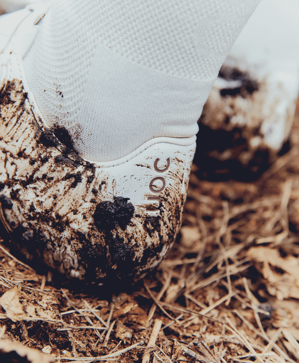 A mud-splattered white QUOC Gran Tourer XC shoe after a ride.