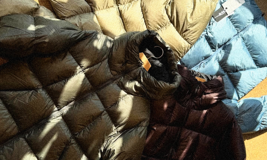 Various puffer jackets in dark green and olive laid out on a flat surface.