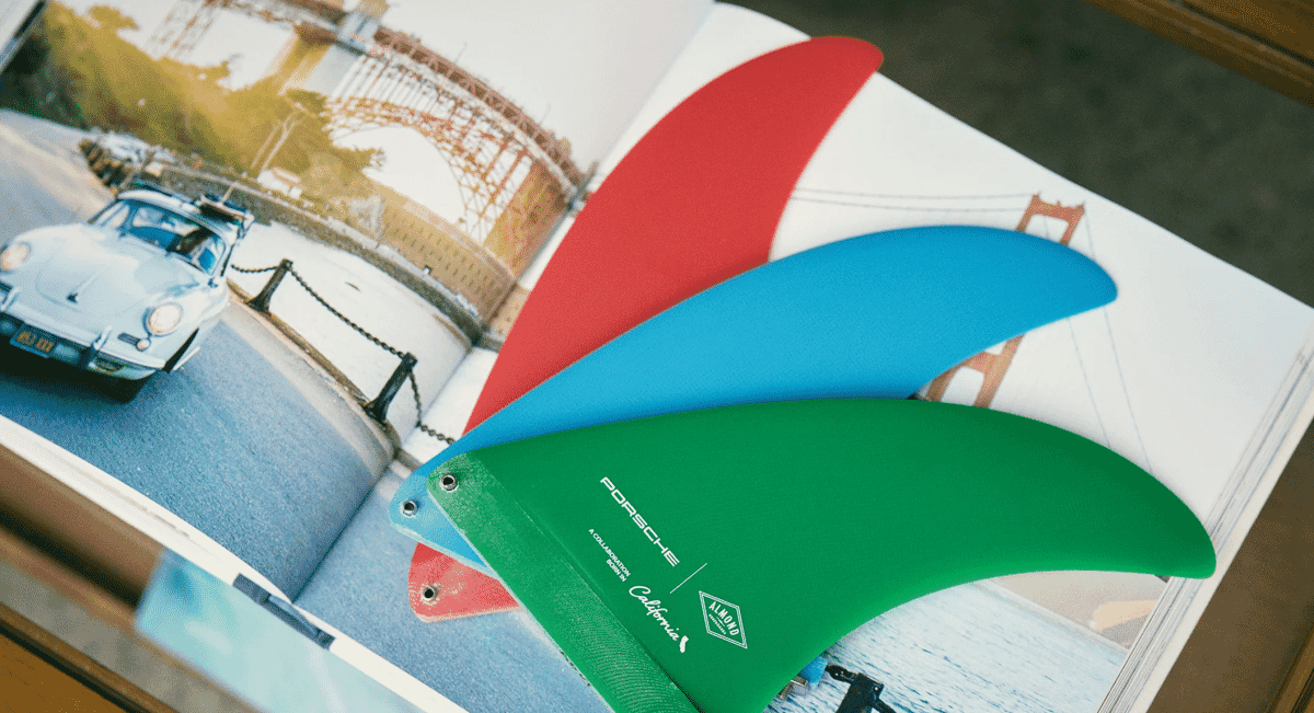 Colorful surf fins on an open photo book featuring vintage cars.