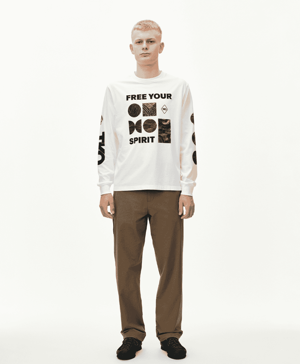 Male model wearing the 'FREE YOUR SPIRIT' graphic long-sleeve tee and brown trousers.