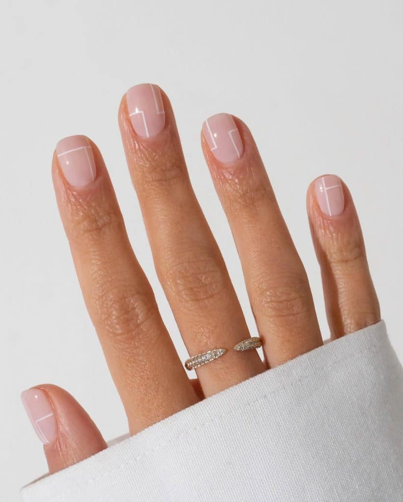 Minimalist geometric nail art on a hand with a diamond-studded ring.