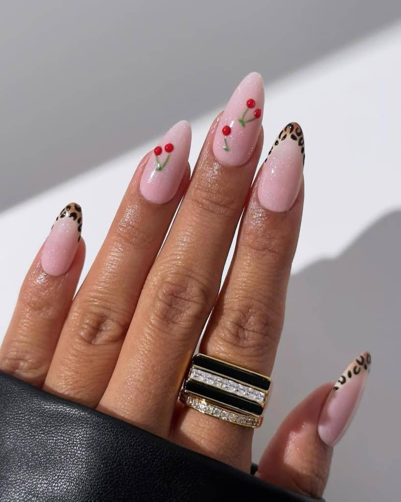 Pink nails featuring a mix of cherry designs and leopard print accents with gold rings.