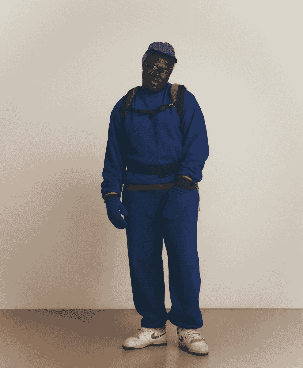 Man wearing a monochromatic blue technical tracksuit, matching beanie, and backpack.