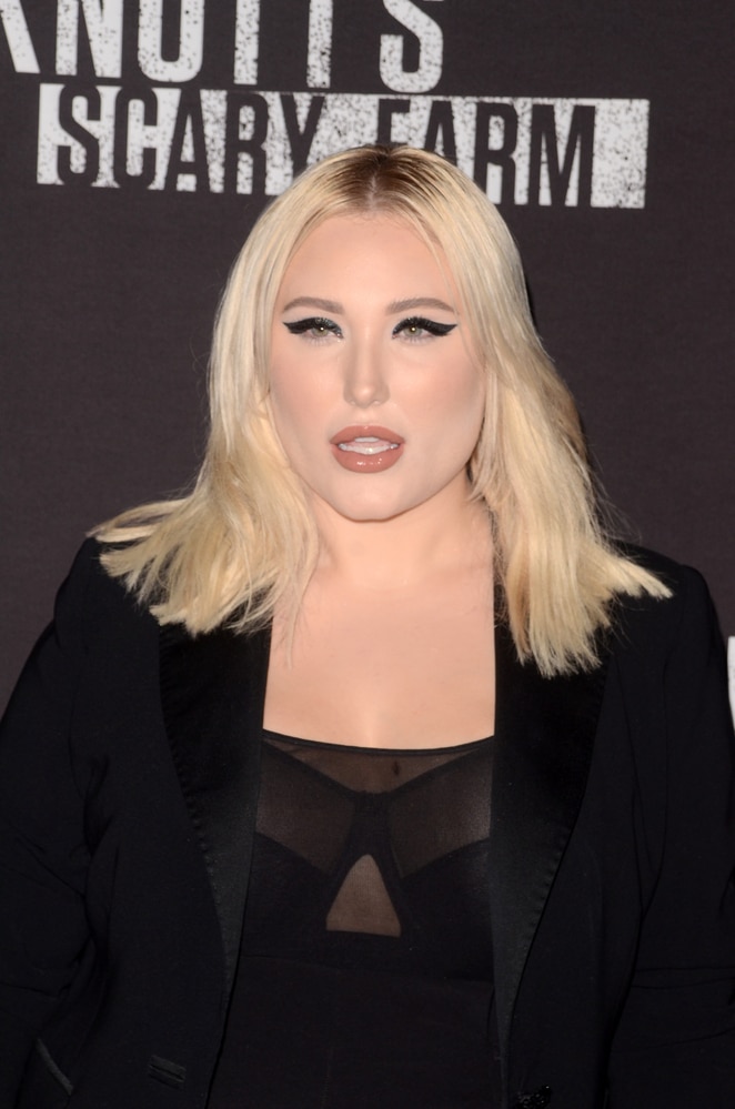 A blonde woman in a tailored black blazer over a sheer top.
