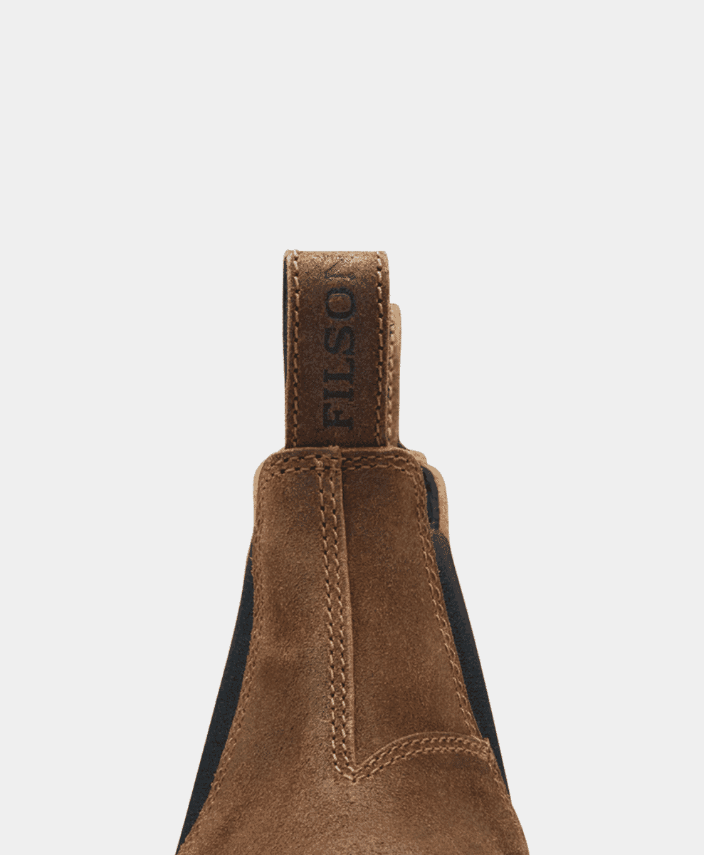 Close-up of the heel pull tab on a suede boot featuring the embossed FILSON logo.