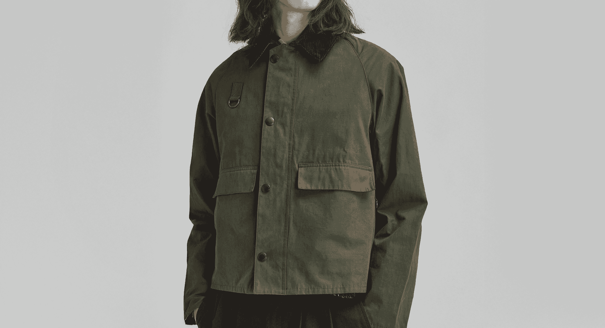 Model with long hair in a dark olive green button-up jacket with a corduroy collar.