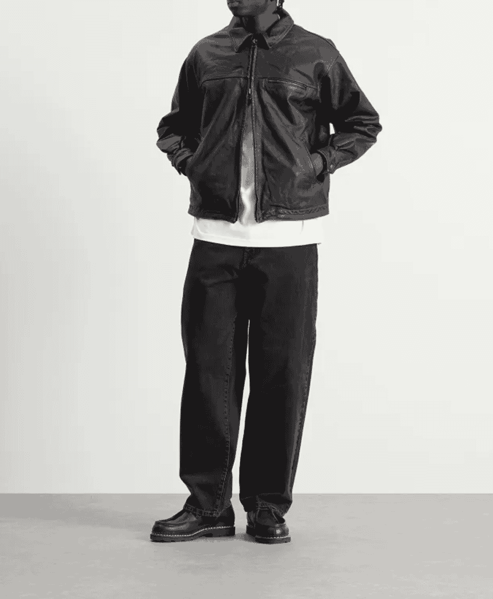 Model in a black leather jacket and dark wide-leg jeans.